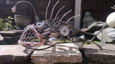 a metal fish sculpture sitting on top of some rocks