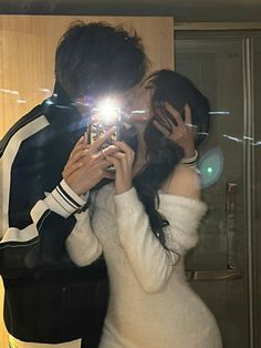 a man and woman taking a selfie in front of a mirror with their cell phone