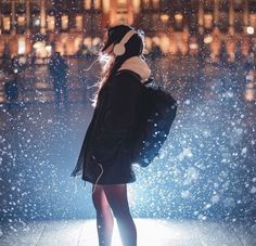 a woman standing in the rain with her back to the camera