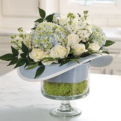a bouquet of white and blue flowers in a glass vase on a counter top with green moss