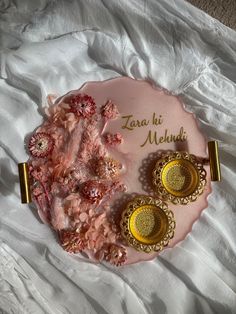 two pairs of earrings sitting on top of a pink plate with gold trimmings