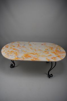 a white and orange marble table with wrought iron legs on grey background, front view