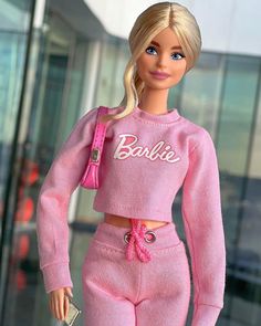 the barbie doll is wearing pink clothing and holding a purse