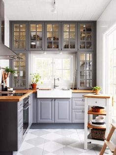 a kitchen filled with lots of gray cabinets and counter top space next to a window