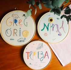 three embroidered hoops with words on them sitting next to a potted plant and napkin