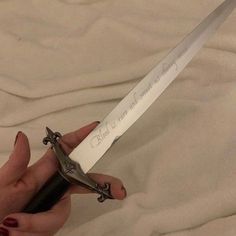 a woman is holding a knife with writing on it and the blade has been cut off