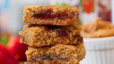 a stack of cookies sitting on top of a table next to a bowl of strawberries