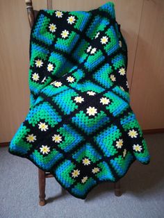 a crocheted blanket sitting on top of a wooden chair
