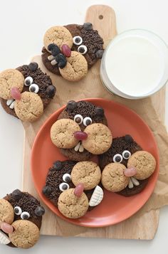 some cookies are on a plate next to a glass of milk and a cutting board