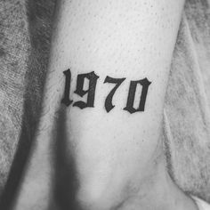 a person with a small tattoo on their arm that reads 1970 and has the number seventy