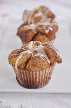 three muffins with icing sitting on top of a white plate next to each other