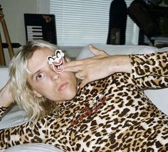 a man laying on top of a white couch wearing a leopard print shirt and tie