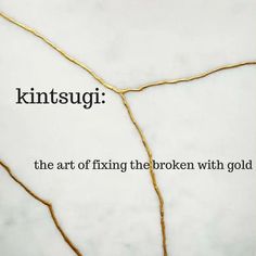 the words kintsugi are written in black ink on a white marble background