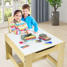 two children sitting at a table with books and pens