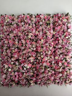 pink and white flowers are arranged in the shape of a flower arrangement on a wall