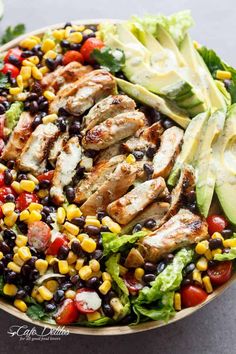 a salad with chicken, lettuce, tomatoes, black beans and avocado