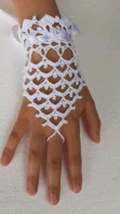 a woman's hand with white crocheted lace on it and a bow at the wrist