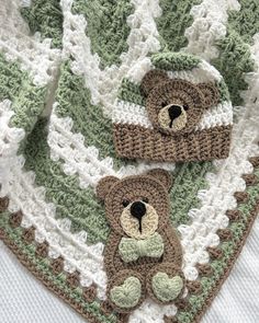 two crocheted teddy bears laying on top of a green and white afghan blanket