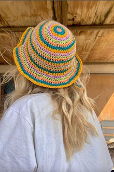 a woman wearing a multicolored crocheted hat looking at the back of her head