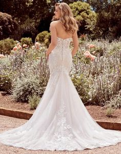 a woman in a wedding dress looking back at the camera while standing on a flower garden