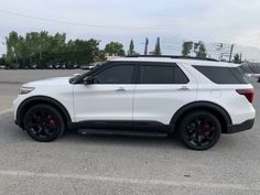 a white suv parked in a parking lot with black rims and red brake pads