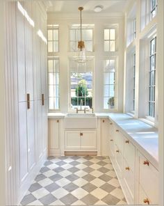 a large kitchen with white cabinets and checkered flooring on the floor, along with windows