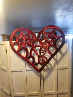 a heart shaped metal sculpture hanging on the side of a white door in a room