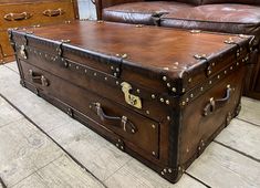 an old trunk is sitting on the floor in front of a leather couch and chair