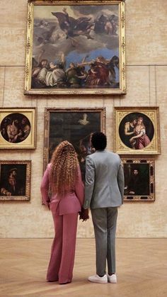 a man and woman standing in front of paintings