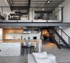 an industrial style kitchen and living room are featured in this photo, while the stairs lead up to the second floor