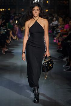 a model walks down the runway in a black dress