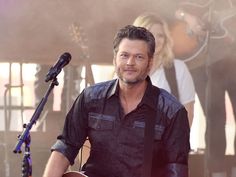 a man standing next to a microphone on top of a stage with other people behind him