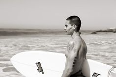 a man standing on the beach holding a surfboard