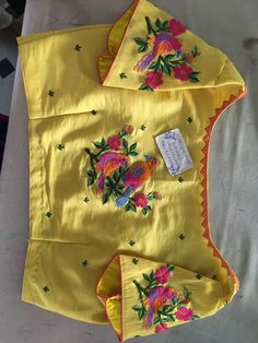 two pieces of yellow cloth with colorful flowers on them and a tag attached to it