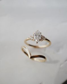 two gold rings sitting on top of a white counter next to an empty glass bottle