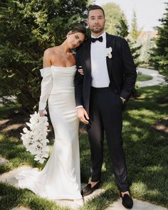 a bride and groom standing in the grass