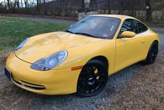 a yellow sports car is parked on the side of the road in front of some trees