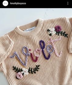 a knitted sweater with flowers and letters on it