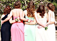 four women in long dresses standing next to each other with their backs turned towards the camera