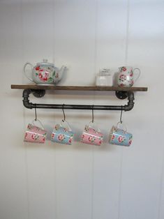 tea cups are hanging on a shelf with hooks