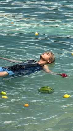 a man floating on top of a body of water surrounded by yellow frisbees