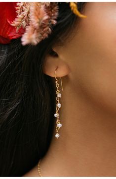 a woman with flowers in her hair wearing gold earrings