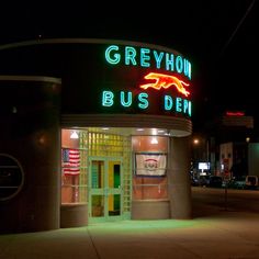 a neon sign on the side of a building that says greyhound bus den at night