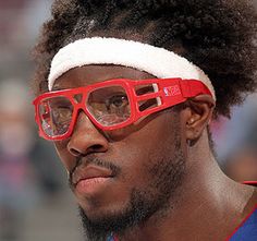 a close up of a person wearing red glasses and a headband with an afro