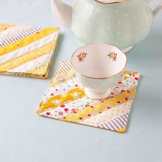 a tea pot and two place mats on a blue table with yellow striped napkins