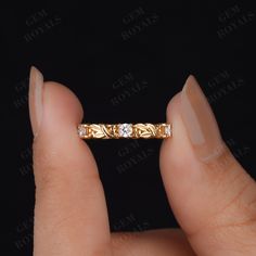 a woman's hand holding a gold ring with two diamonds on it and the band is