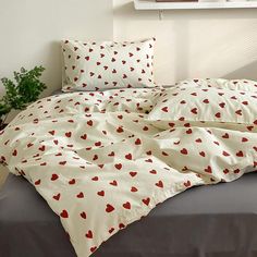 an unmade bed with red hearts on it in a white and gray bedroom area