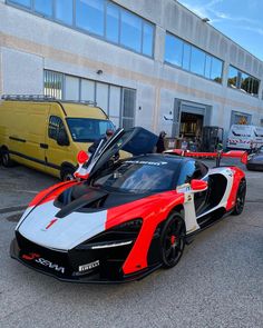 a red and white sports car parked in front of a building next to other cars