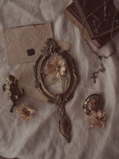 an old fashioned mirror, rosary, and other items are laying on a white sheet