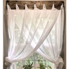 a window with white sheer curtains hanging from it's side